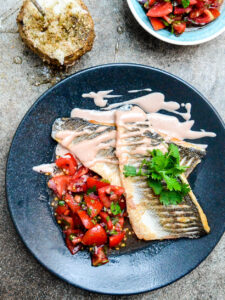 Pan fried sea bass with tahini sauce and tomato salad seen from above