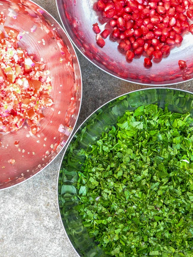 Bowls with prepared ingredients for tabbouleh – 1 herbs 2 bulgur and tomato 3 pomegranate seeds