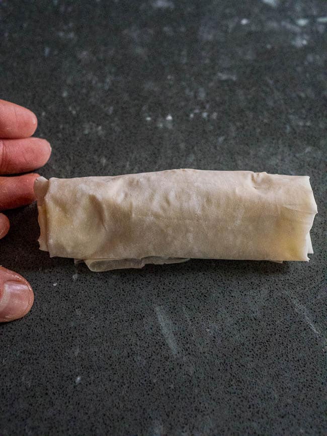 Hand showing final result of rolled cigar style borek