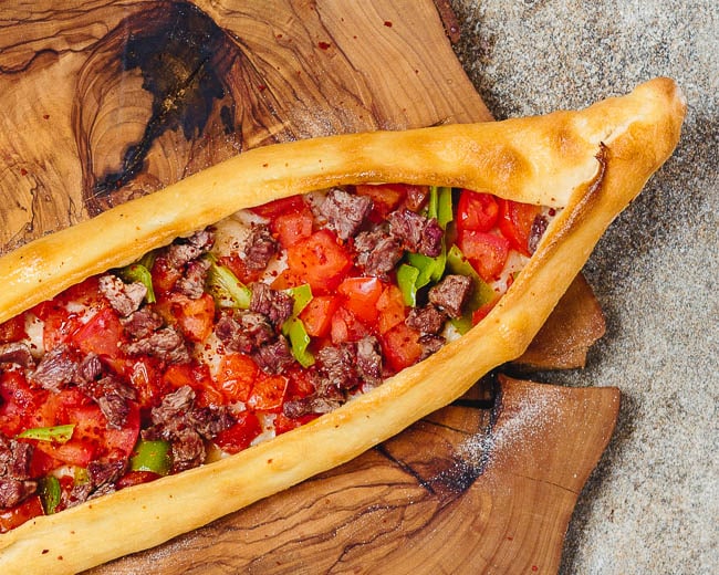 Oval Turkish pide with meat, tomato and peppers