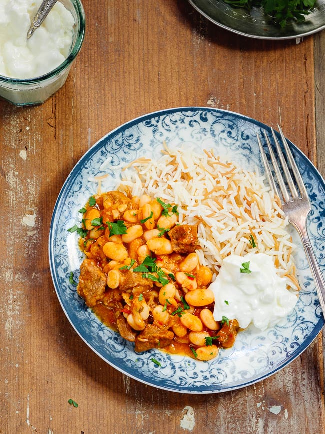 Turkish white bean stew with rice and yoghurt on a patterned blue plate, seen from above