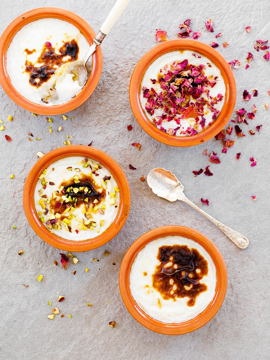 Four bowls of Turkish rice pudding on gray stone, seen from above