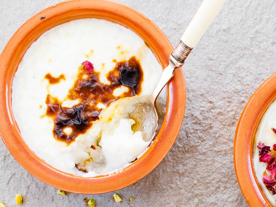 One bowl of Turkish rice pudding with a spoon taking out a part and showing the inside, seen up close from above