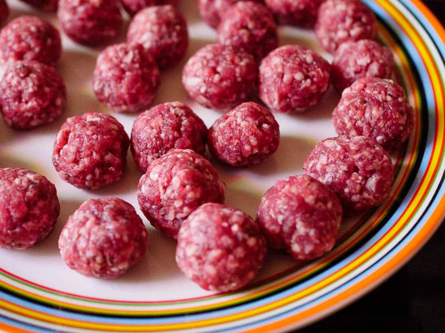 Shaped raw meatballs on colourful plate