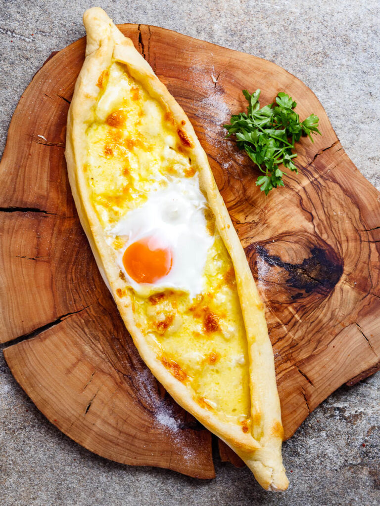 Baked Turkish cheese pide on wooden board, seen from above