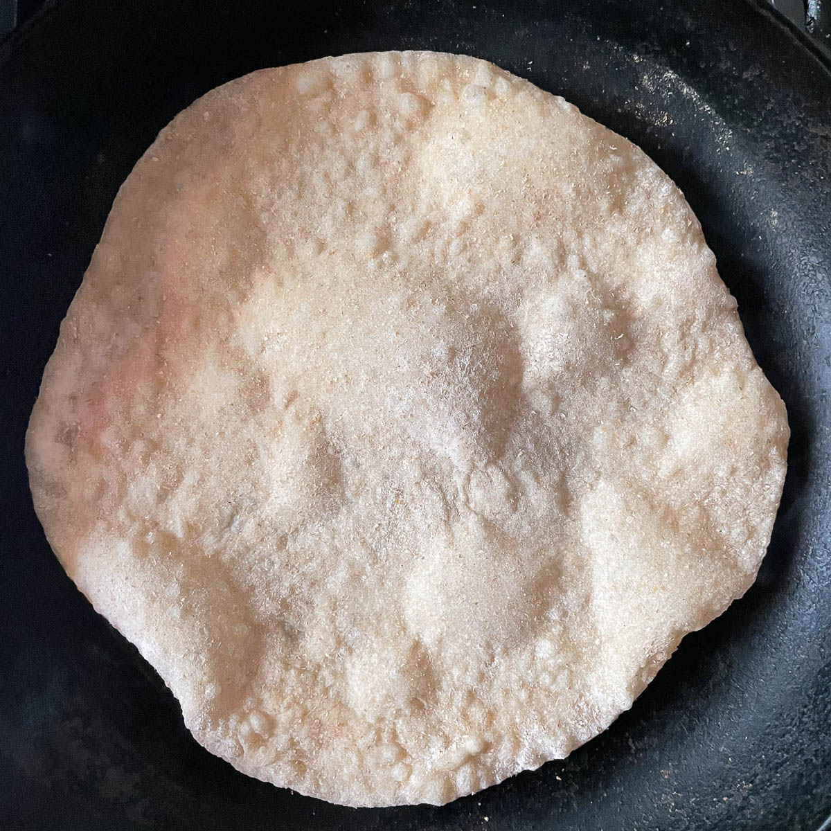 Armenian lavash flatbread cooking in a pan with uncooked side up