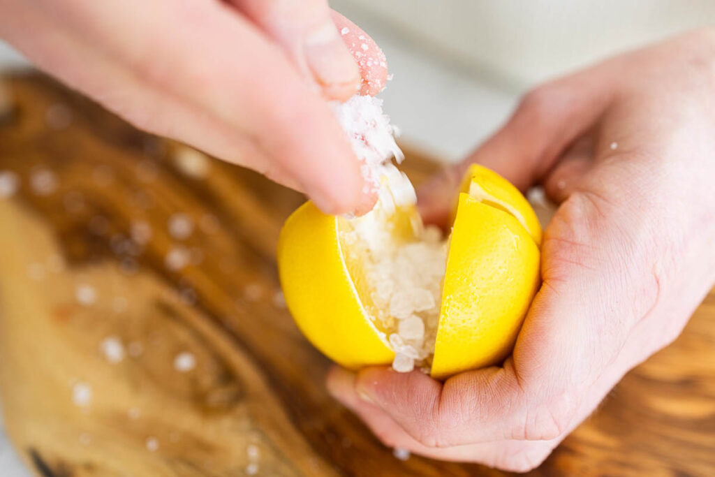 Adding coarse salt to lemons.
