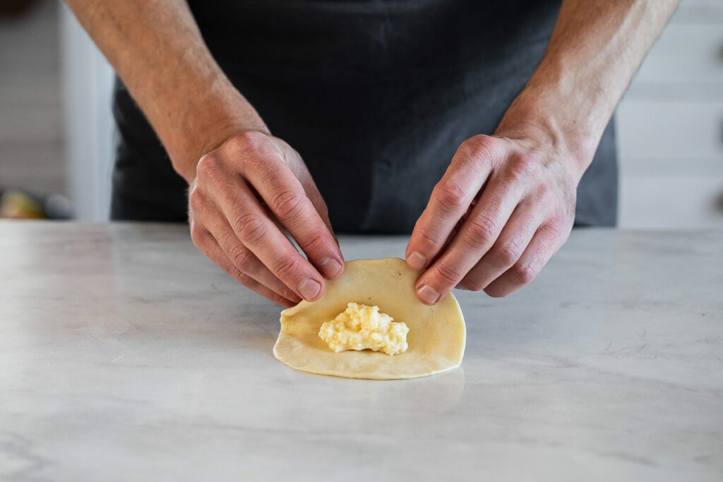 Person folding pogaca dough over the filling