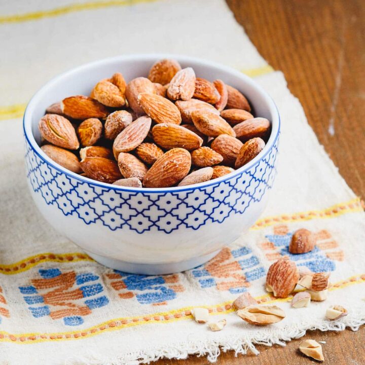 Roasted salted almonds in a small bowl, seen from the side