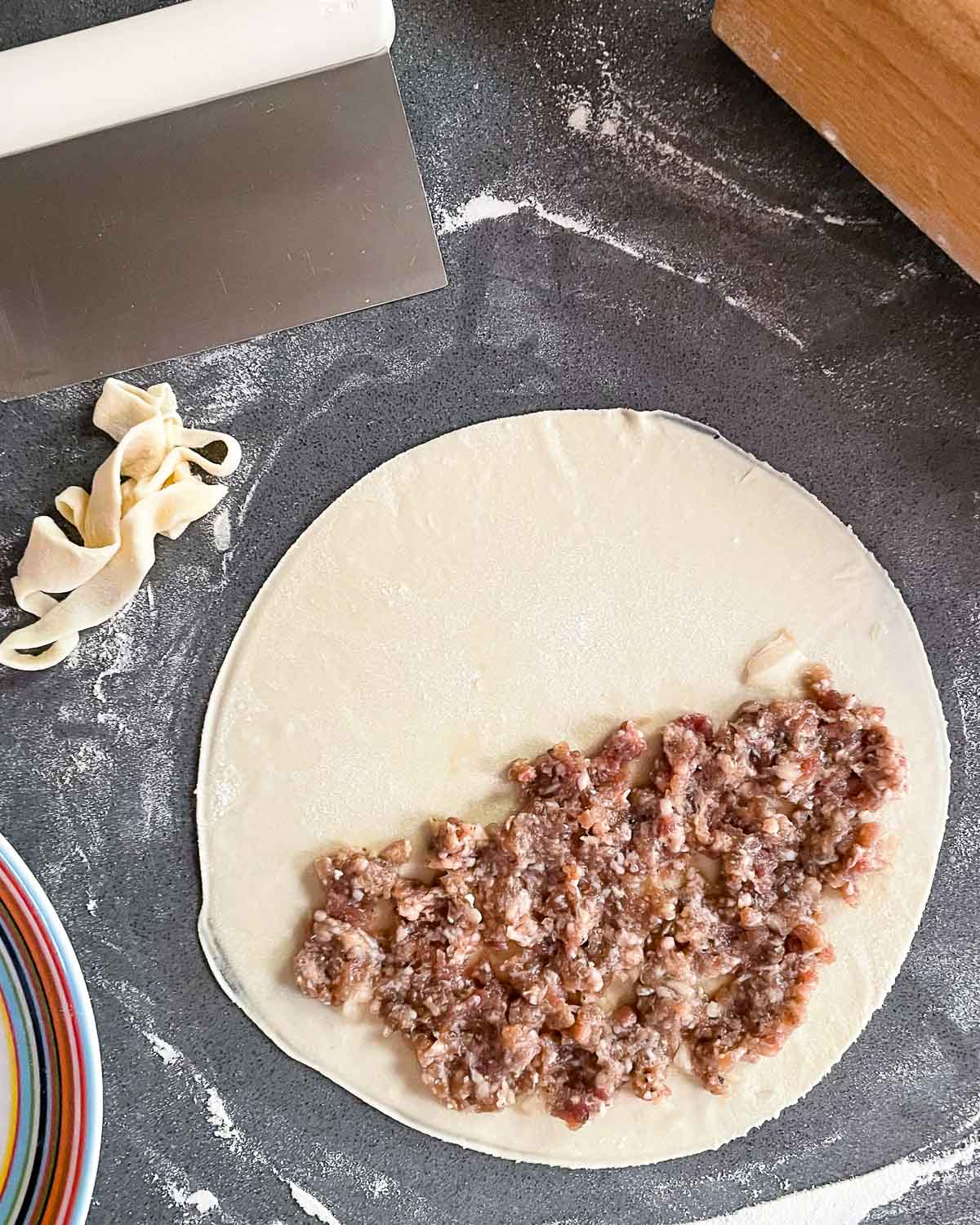 A circular piece of dough with filling on half of it.